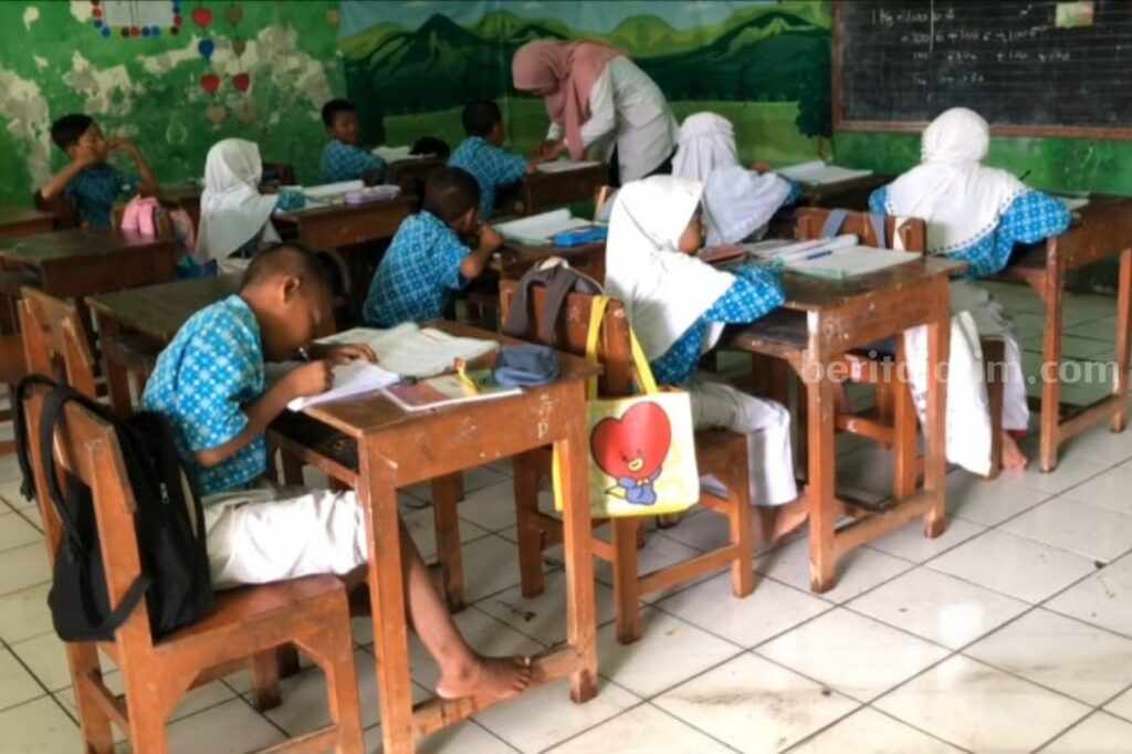 Para siswa SDN di Lamongan yang tetap belajar meski sekolahnya tergenang banjir (Foto: A. Thoriq Hidayatullah/beritajatim.com).