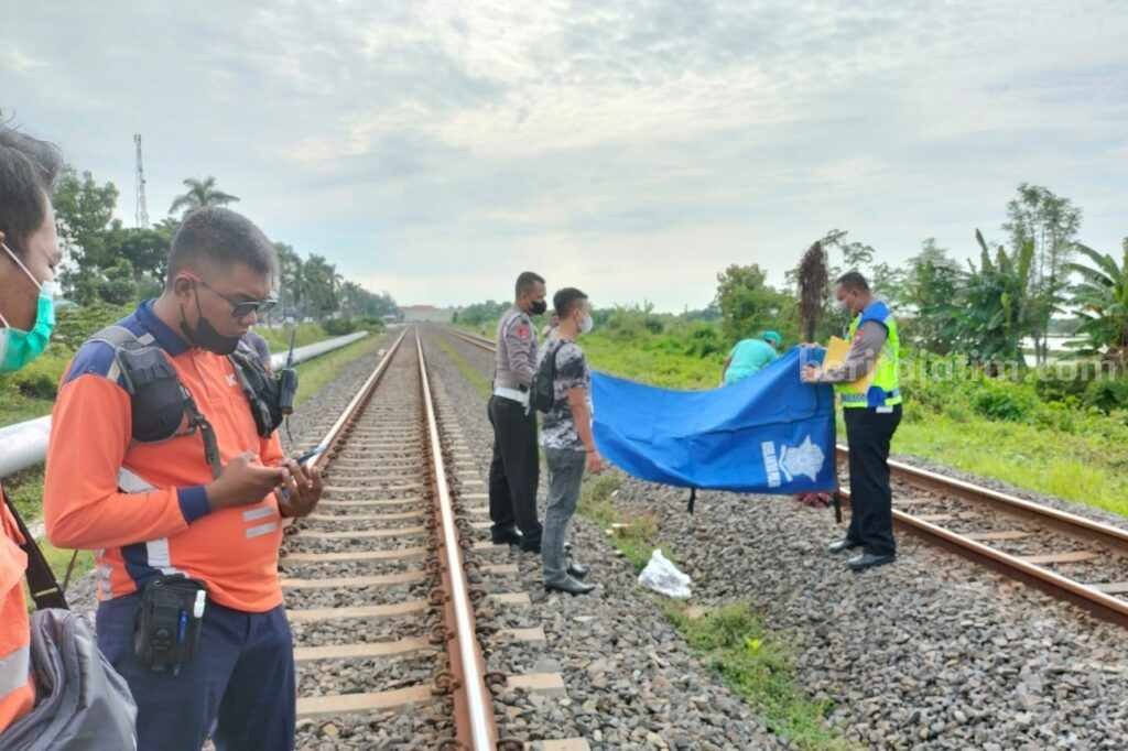 Polisi saat mengevakuasi mayat tanpa identitas yang diduga tewas karena tertabrak KA di perlintasan Lamongan (Foto: A. Thoriq Hidayatullah/beritajatim.com).