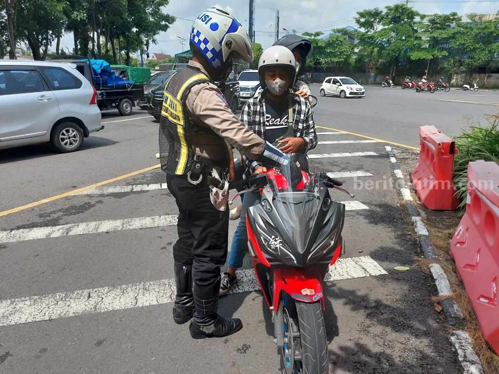 Di Surabaya, Ini Sanksi Bagi Pengendara yang Pasang Pelat Nomor Palsu Anggota polisi menilang pengendara