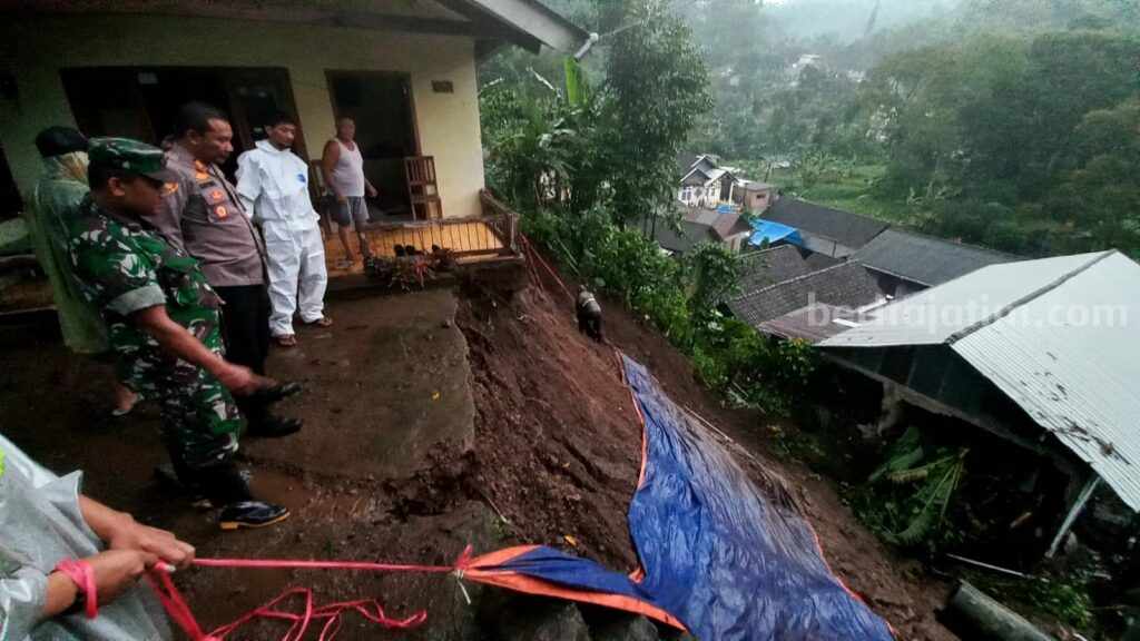 Petugas kepolisian beserta BPBD dan warga saling bahu membahu membersihkan material longsor dan menutup terpal.