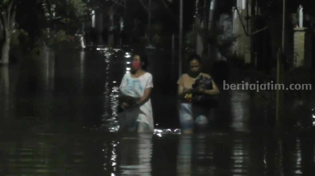 Banjir di Gresik Belum Surut, Sejumlah Desa Malah Terisolir Dua warga Desa Tambakberas, Kecamatan Cerme, Gresik, sedang berjalan saat banjir menerjang
