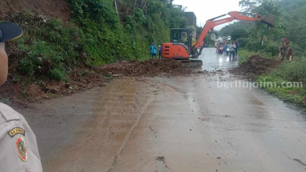 Sejumlah petugas mengevakuasi material tebing longsor di Jalan Raya Dusun Kambengan, Desa Cempokolimo, Kecamatan Pacet, Kabupaten Mojokerto longsor. [Foto : ist]