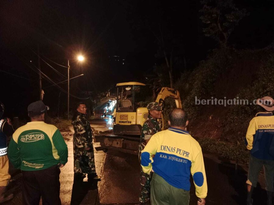 Petugas membersihkan tanah longsor yang ada di jalan
