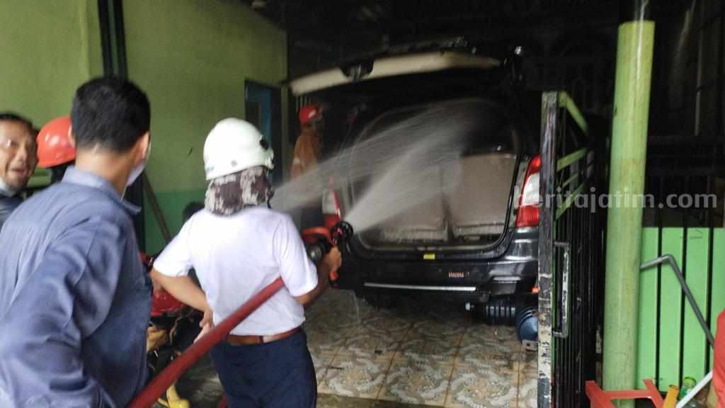 Petugas damkar Gresik sedang memadamkan kap mesin mobil yang terbakar