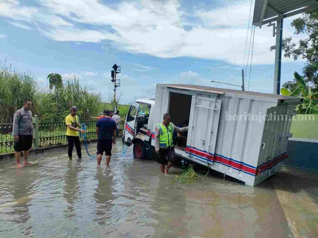 Anggota Polsek Prajurit Kulon bersama warga mengevakuasi truck box nopol N 9458 GD yang terperosok di saluran irigasi di Jalan Raya Trenggilis, Kecamatan Prajurit Kulon, Kota Mojokerto. [Foto : ist]