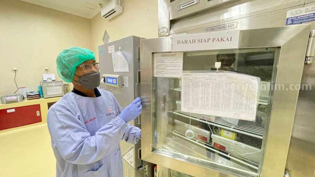 Petugas PMI Gresik sedang memeriksa stok darah di mesin pendingin.