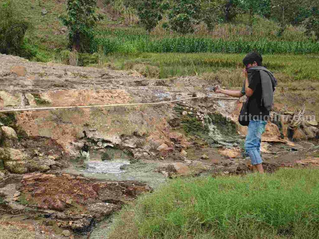 Seorang sedang mendokumentasikan semburan air yang mengandung gas.