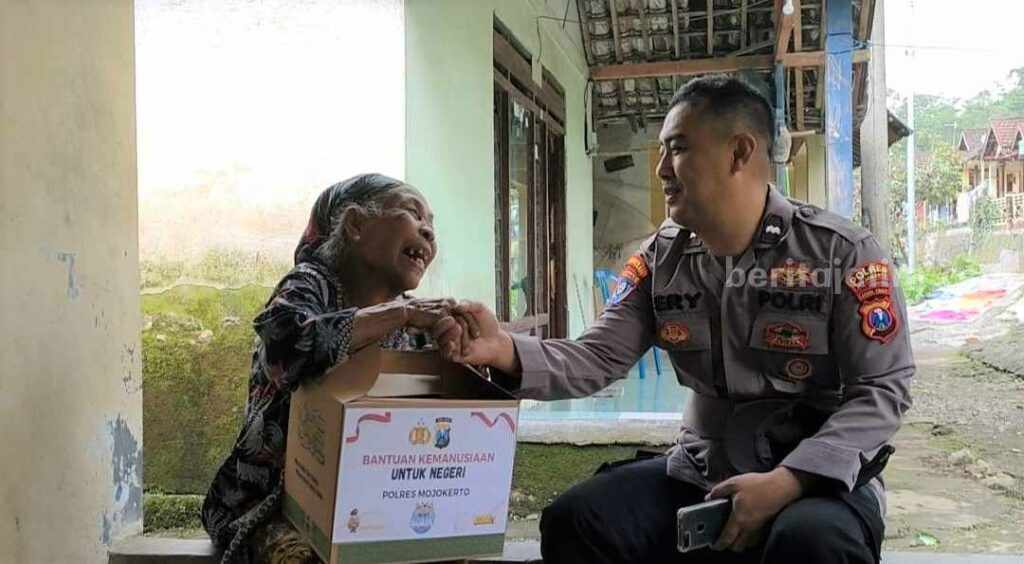 Anggota Polsek Trawas memberikan paket sembako kepada warga. [Foto : ist]