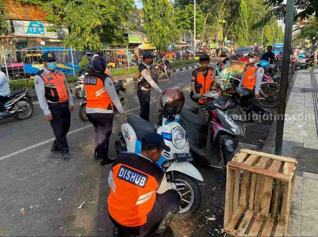 Petugas Dinas Perhubungan (Dishub) Gresik sedang menggembosi ban motor yang diparkir sembarangan