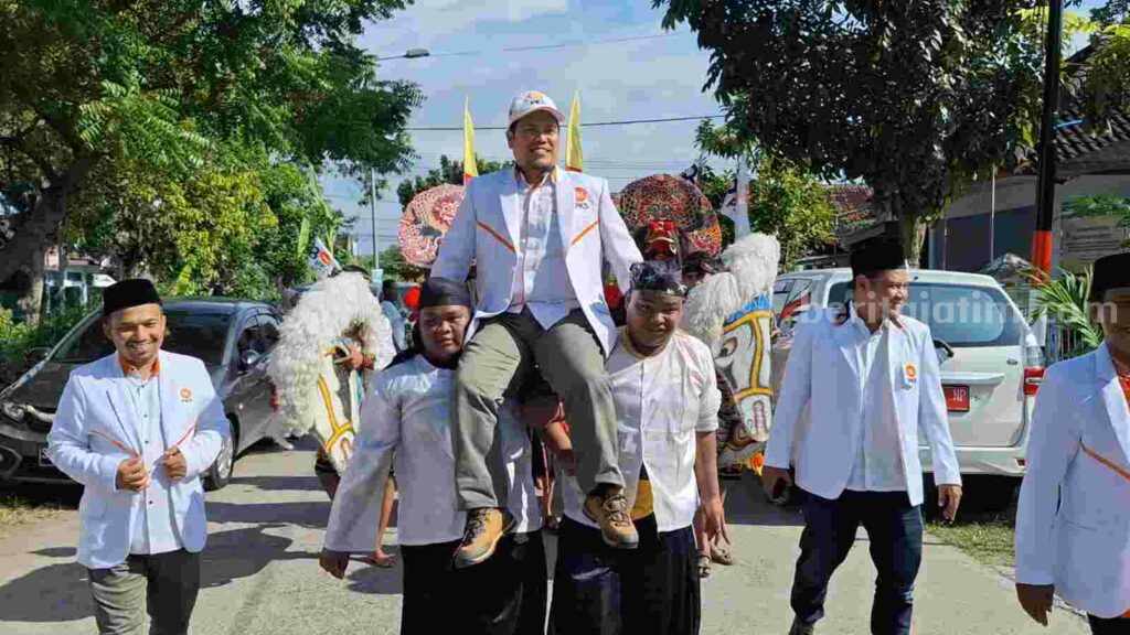 Ketua DPD PKS Kabupaten Mojokerto, Imam Sutarso dipanggul dengan diiringi kesenian kuda lumping dan barongan ke kantor KPU Kabupaten Mojokerto. [Foto : Misti/beritajatim.com]