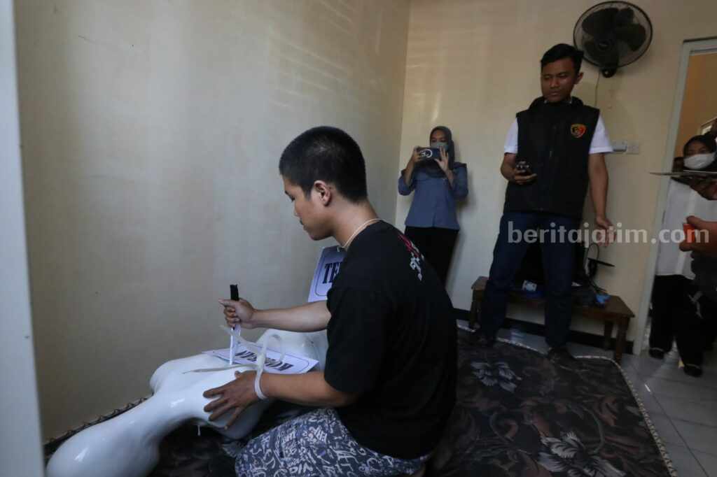 Pria Gresik Ini Berdoa Sebelum Bunuh Anak Kandung, Juga Lihat Tutorial di Internet Pelaku saat melakukan adegan rekontruksi menusuk anak kandung dengan menggunakan pisau dapur yang telah diasah.