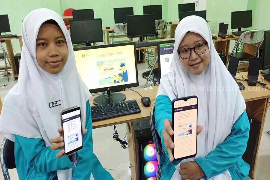 Etik Nurhasanah (kiri) dan Like Zuyyina Fatwa Fadila (kanan) saat menunjukkan pengumuman diterimanya mereka di kampus Taiwan, yakni National Taiwan University. (Foto/Endra Dwiono/Beritajatim.com)