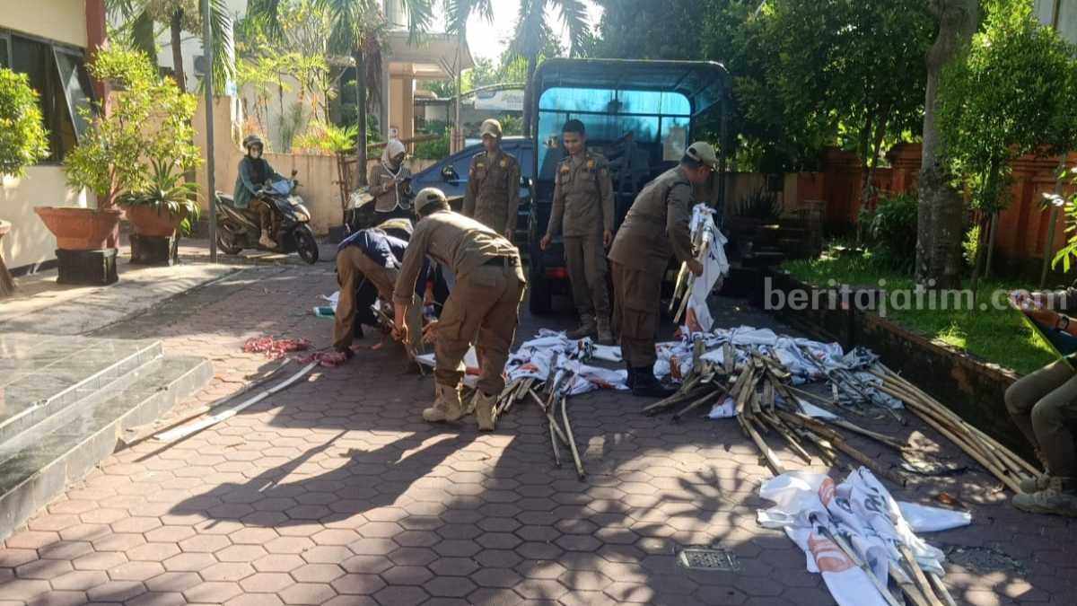 Anggota Satpol PP Kota Mojokerto mengamankan bendera parpol di jalan protokol Kota Mojokerto. [Foto : ist]