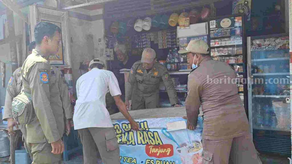 Anggota Satpol PP Kota Mojokerto membawa sejumlah peralatan milik PKL ke truk. [Foto : Misti/beritajatim.com]
