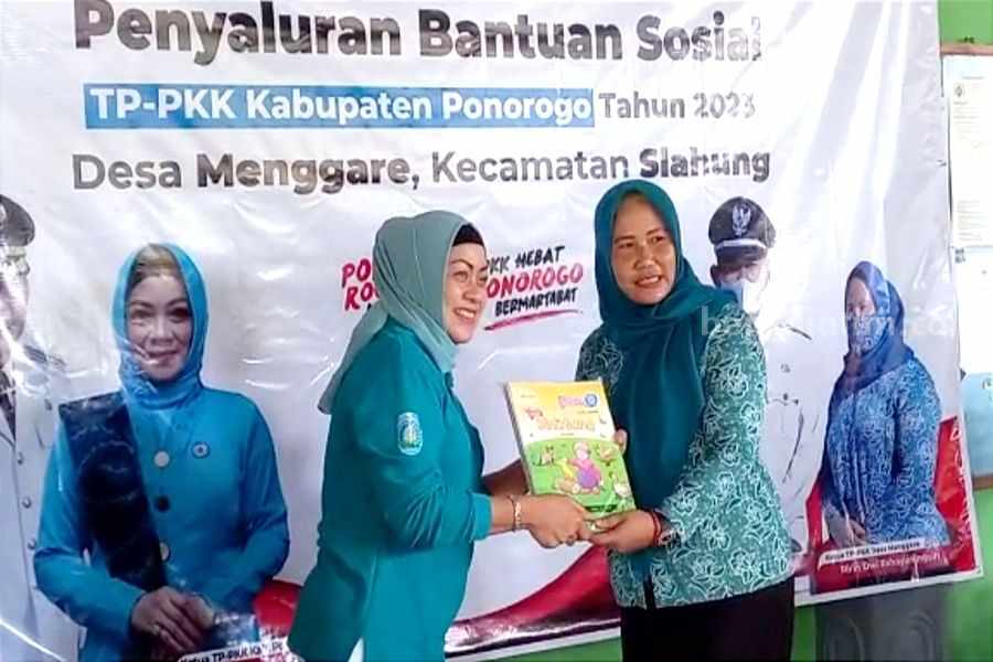 Ketua TP PKK Ponorogo Susilowati Sugiri Sancoko (kiri) saat memberikan buku bacaan di Desa Menggare Kecamatan Slahung. (Foto/Endra Dwiono/Beritajatim.com)
