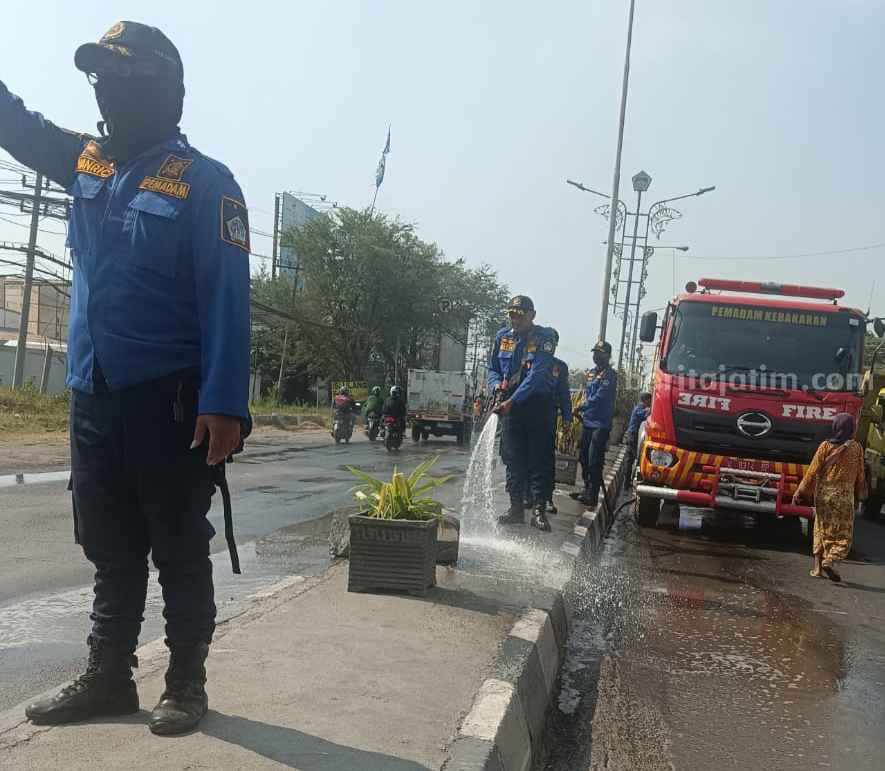 Petugas Damkarla Gresik saat membersihkan Jalan Manyar yang akan dilalui Presiden Jokowi