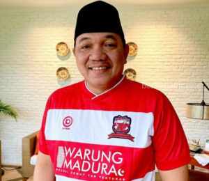 Bos Madura United FC, Achsanul Qosasi dengan jersey loreng khas Laskar Sape Kerrab dengan tulisan 'Warung Madura'. [Gambar: IG Achsanul Qosasi]