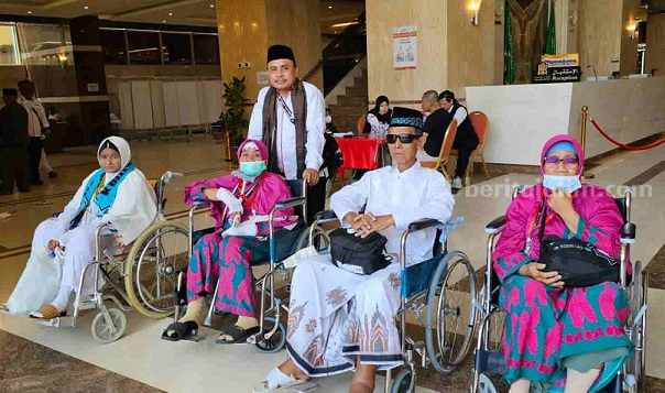 Almarhum Murzuq (duduk di kursi roda) saat berada di tanah suci bersama jamaah lainnya dan didampingi Kasi PHU, Kemenag Kabupaten Mojokerto, M Zainut Tamam. [Foto : ist]