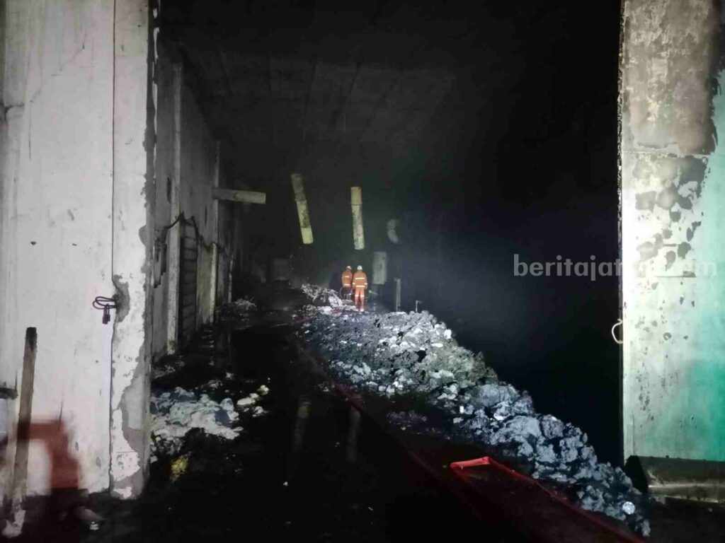 Petugas dari Damkar BPBD Kabupaten Mojokerto melakukan pemadaman di pabrik benang untuk pembuatan sarung tangan. [Foto : ist]