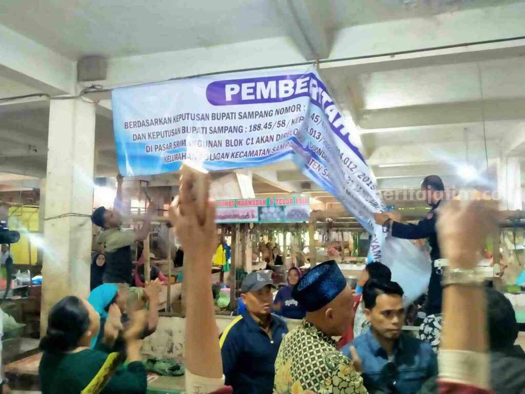 Penurunan baliho rencana relokasi pedagang pasar Srimangunan (Foto: Zamachsari/beritajatim.com)