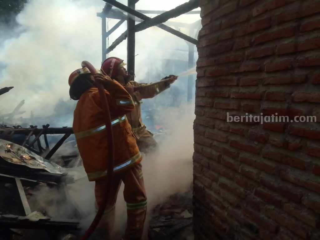 Petugas saat melakukan pembasahan lokasi kebakaran.