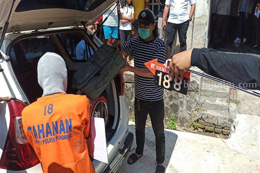Tersangka saat menjalani rekonstruksi dengan adegan memasukkan koper ke mobil. (Foto/Endra Dwiono)