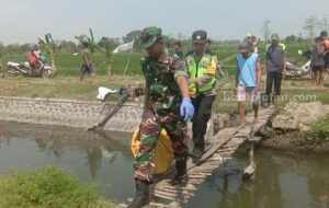 Anggota TNI dan Polri mengevakuasi jasad bocah yang tersangkut di Sungai Desa Gongseng Kecamatan Megaluh, Minggu (2/7/2023)