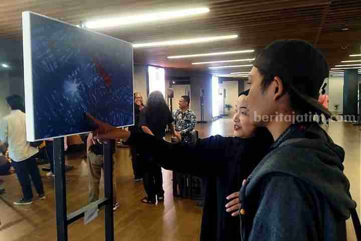 Potret pengunjung yang sedang melihat salah satu karya di pameran foto "Tutur Mata", di Basement Alun-alun Surabaya, Jumat (28/7/2023). (Foto: Fitri Yuliani/beritajatim.com)