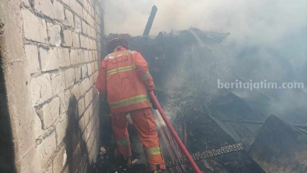 Petugas Damkarla Gresik sedang berjibaku memadamkan rumah pengasapan ikan yang dilalap api