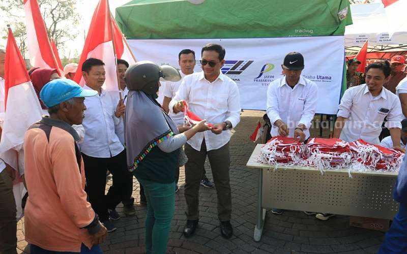 Direktur Utama PT JGU, Mirza Muttaqien membagikan bendera ke masyarakat