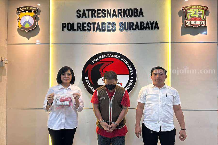 EW (tengah) saat diamankan di Polrestabes Surabaya.
