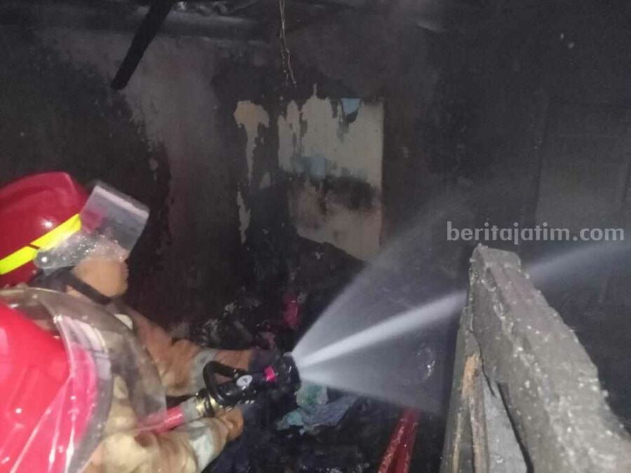 Petugas Damkarla Kabupaten Gresik sedang memadamkan api yang menghanguskan rumah kos akibat korsleting listrik