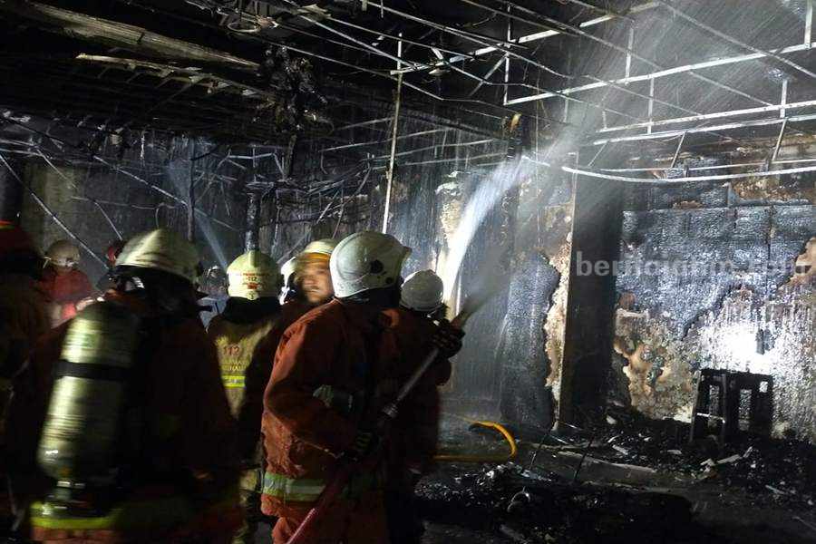Petugas dari DPKP Kota Surabaya saat melakukan pembasahan di lantai 1 Gedung BBPMP Jatim, Jalan Ketintang, Minggu (27/08/2023) dini hari.