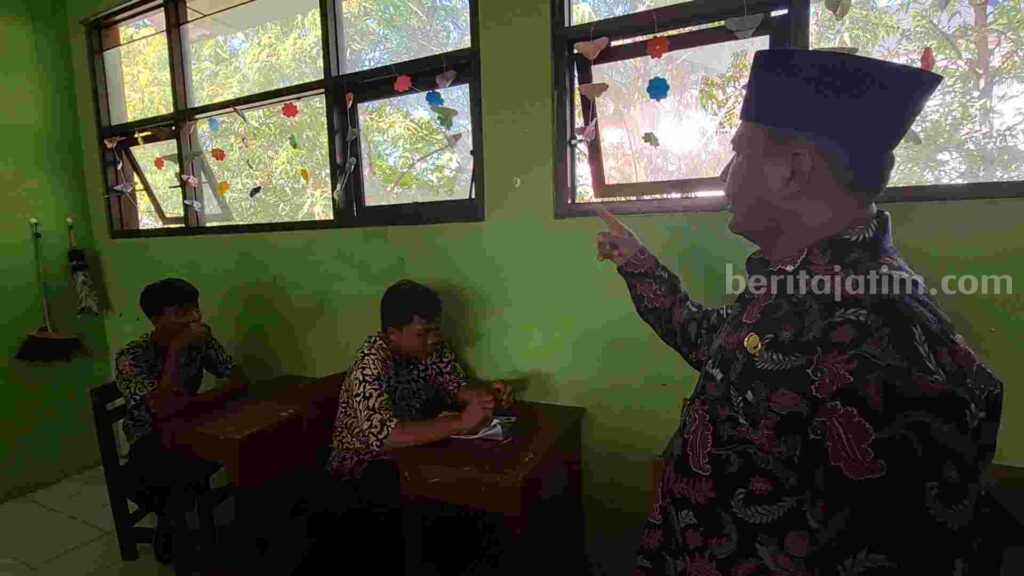 Kepala MAN Kota Mojokerto, Abdul Salam menunjukkan kaca kelas F (XI 4) yang pecah akibat lemparan batu. [Foto : Misti/beritajatim.com]