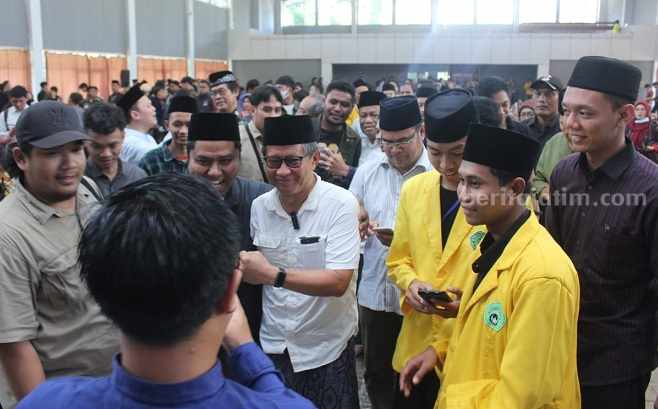 Peci dan Sarung untuk Rocky Gerung Ketua Pelaksana Mimbar Mahasiswa, Muhammad Satrio Qolbi Seto (kanan), saat mendampingi Rocky Gerung, Selasa (1/8/2023)