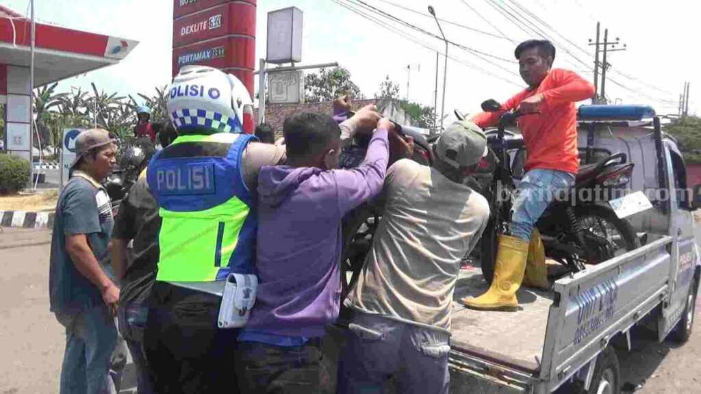 Petugas dibantu relawan dan warga mengevakuasi sepeda motor milik korban. [Foto : ist]