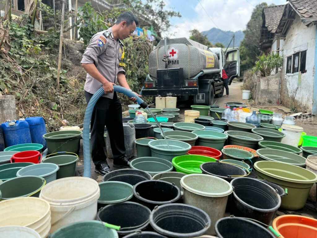 Anggota Polres Malang, mengisi ember plastik milik warga Jabung, Kabupaten Malang yang kesulitan air bersih di musim kemarau, Jumat (29/9/2023).