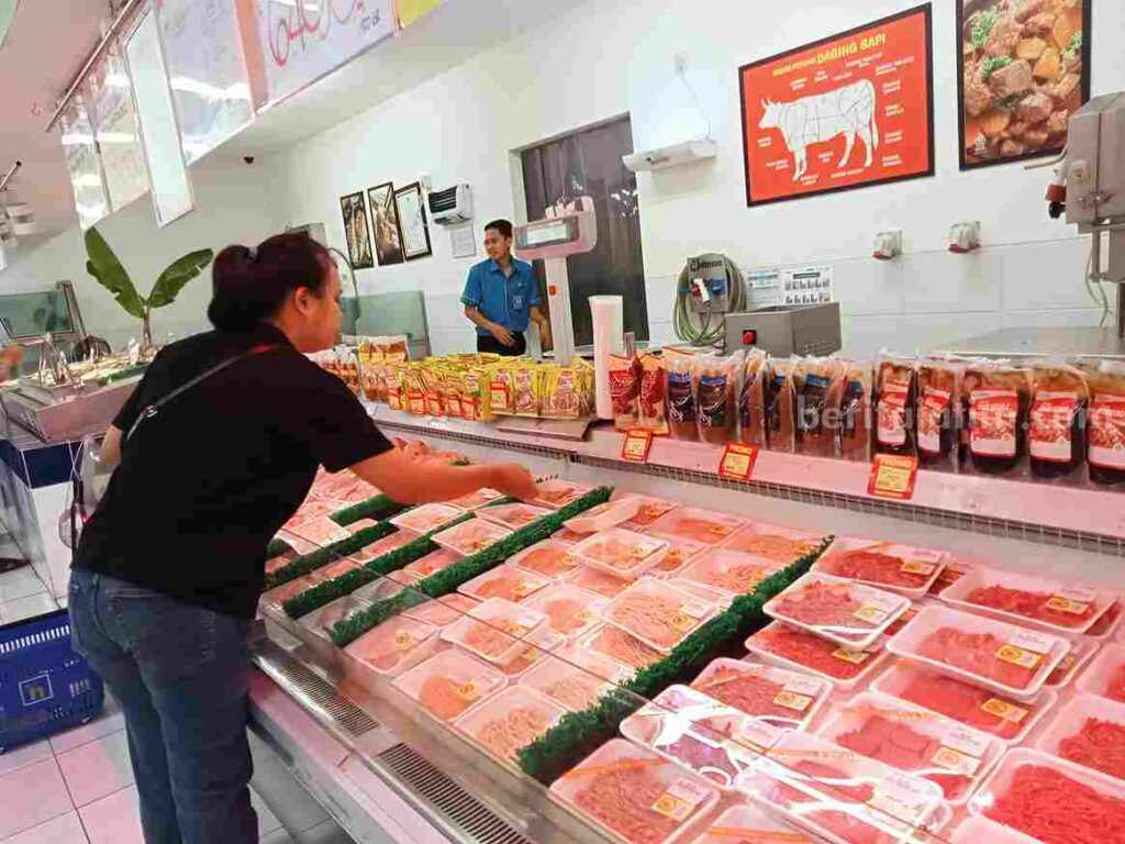 Seorang ibu rumah tangga sedang memilih daging yang di salah satu retail modern