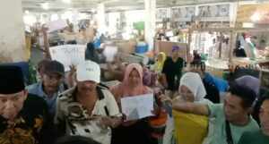 Pasar Srimangunan Sampang Banjir Tulisan Tolak Relokasi Pedagang pasar Srimangunan bentangkan tulisan tolak relokasi (Foto: Zamachsari/beritajatim.com).