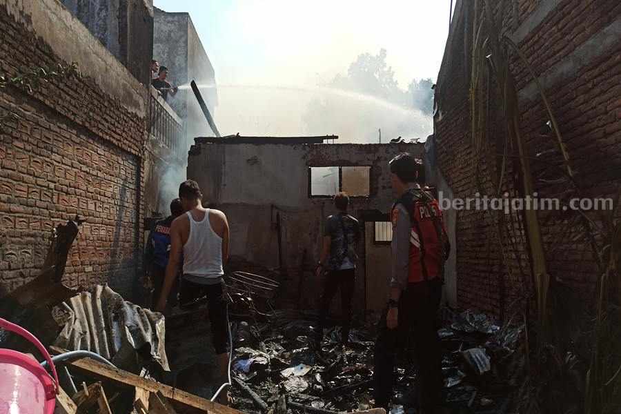 Petugas melakukan pembasahan di rumah yang terjadi kebakaran. (Foto/Endra Dwiono/Beritajatim.com)