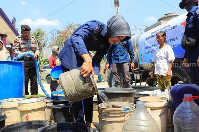 Humas Polres Tuban saat membantu masyarakat menerima air bersih.
