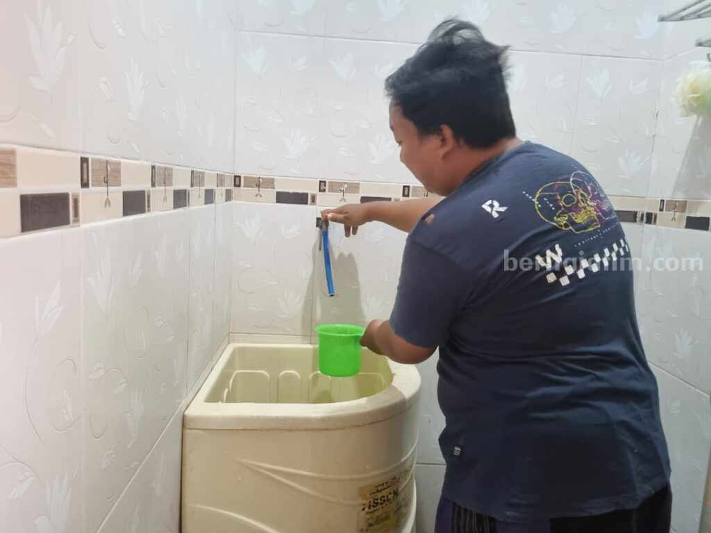 Foto seorang warga sedang memutar kran bak mandi tapi tak keluar air