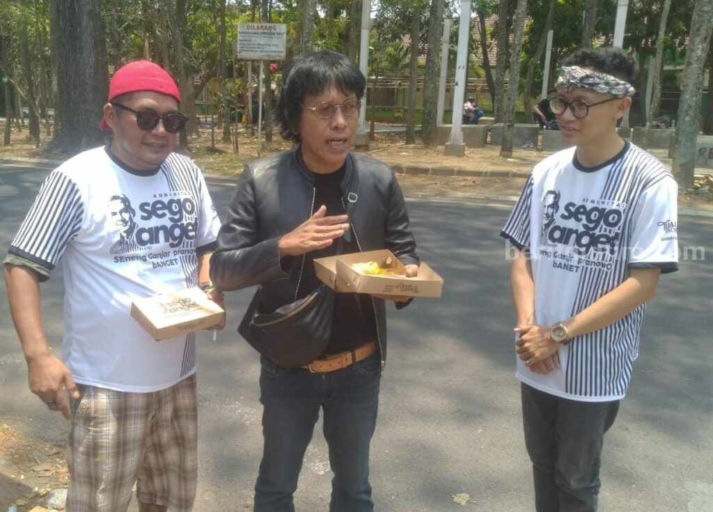 Politisi senior Adian Napitupulu, saat ikut membagikan Sego Anget di sela kunjungan Capres Ganjar Pranowo di Kota Malang, Senin (16/10/2023).