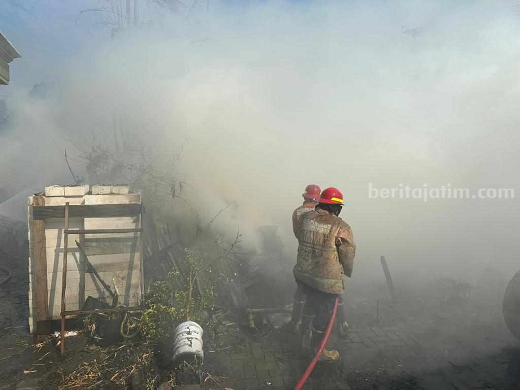 Petugas Damkarla Gresik berusaha memadamkan api yang menghanguskan gudang kayu.