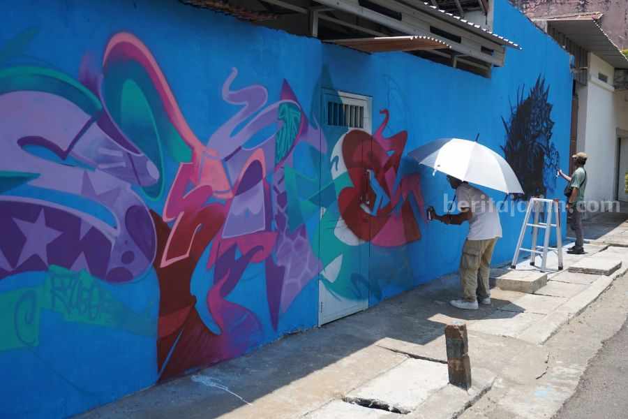 Tubgraff bersama seniman visual dari berbagai kota di Indonesia yang sedang menghias dinding di kawasan nelayan Tuban. (Foto: Diah Ayu/beritajatim.com)