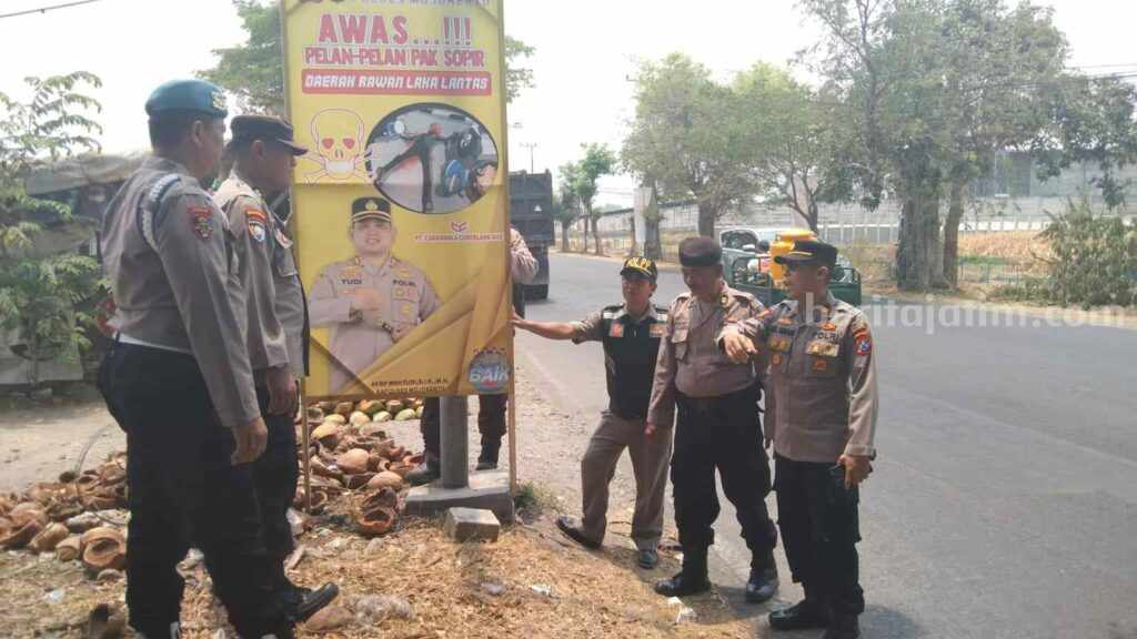 Caption : Anggota Polsek Dlanggu memasang banner himbauan di Jalan Raya Pekingan, Desa Sumbersono, Kecamatan Dlanggu, Kabupaten Mojokerto. [Foto : ist]