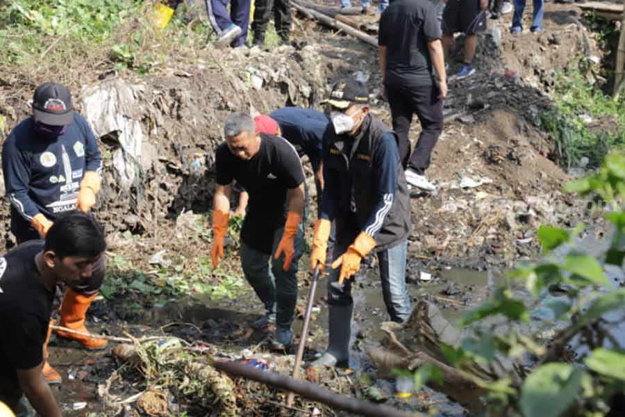 Pj Wali Kota Malang, Wahyu Hidayat saat membersihkan sampah di sungai.