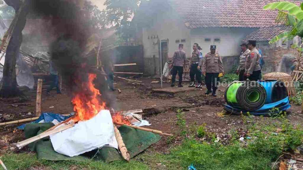 Petugas membongkar dan membakar tempat yang diduga digunakan sebagai arena judi sabung ayam di Dusun Brenet, Desa Watukenongo, Kecamatan Pungging, Kabupten Mojokerto. [Foto : ist]