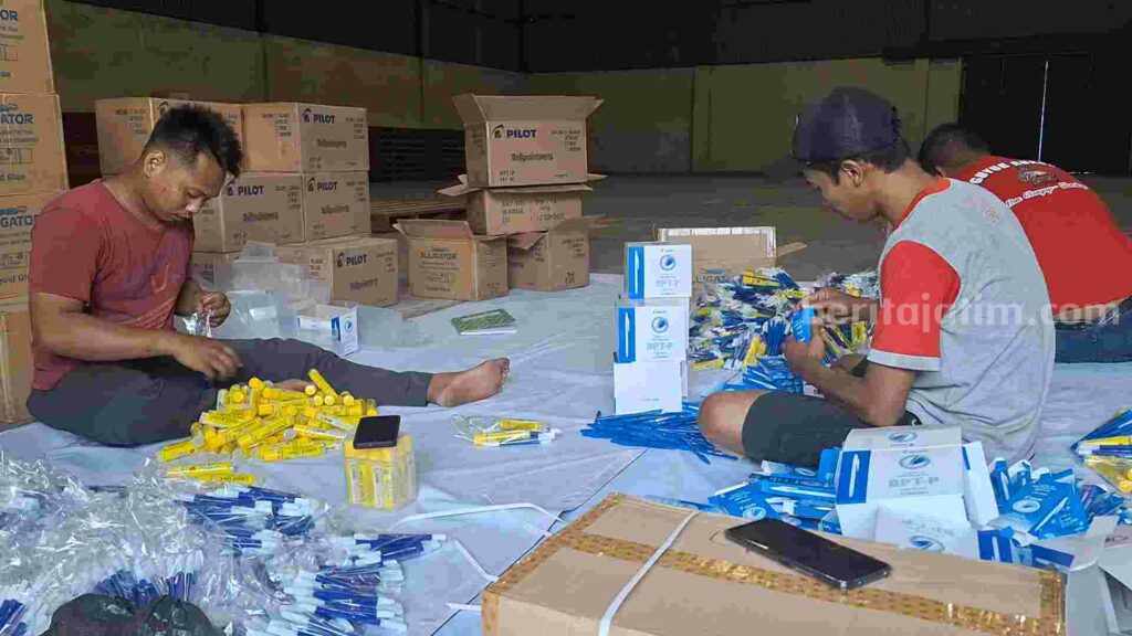 Caption : Sejumlah petugas menggemas APK Pemilu 2024 di gudang Perum Bulog Sub Divre Surabaya Selatan. [Foto : Misti/beritajatim.com]