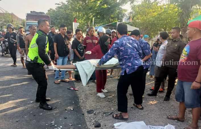 Petugas kepolisian saat mengevakuasi korban laka yang tewas di TKP usai adu montong sesama sepeda motor, di Lamongan.